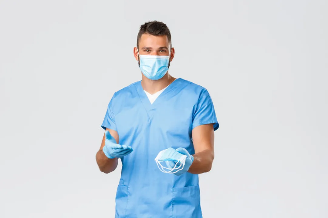 A man in blue scrubs reaches out with PPE masks