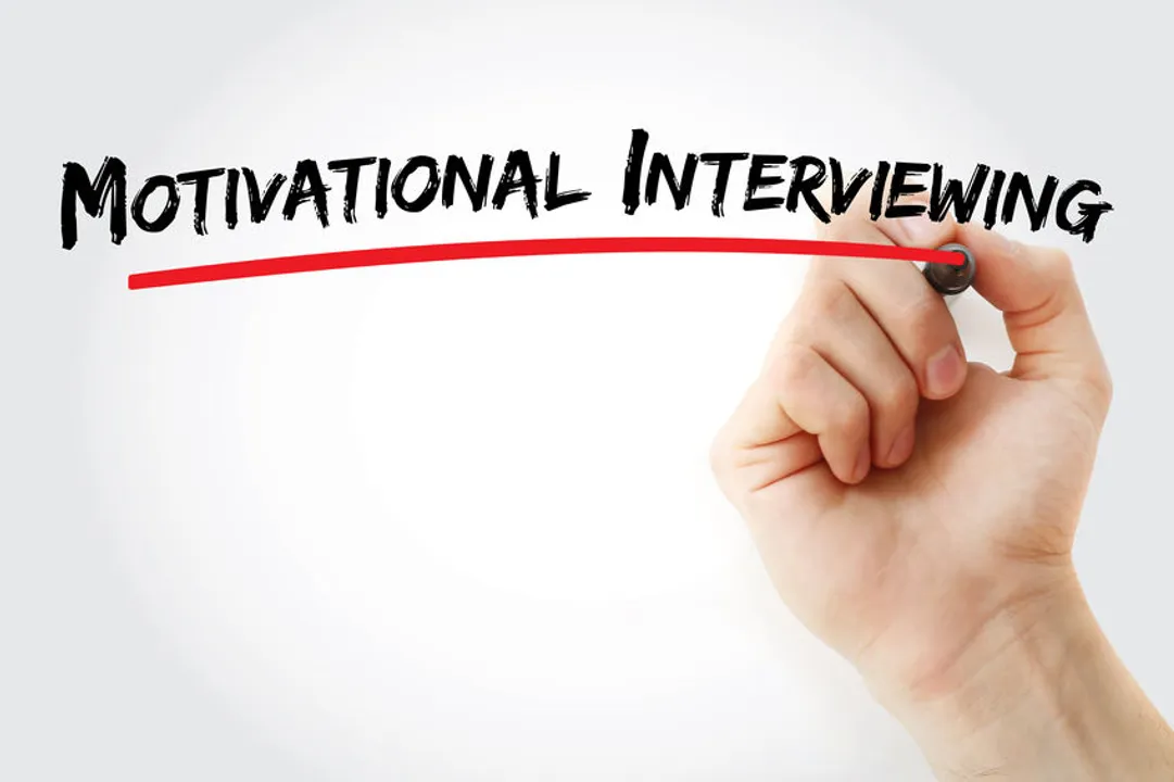 A hand and marker write the text, "motivational interviewing." The article discusses how concepts of motivational interviewing can be incorporated and can benefit physician recruitment