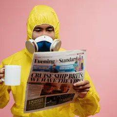 A man in a yellow hazmat suit reads the paper