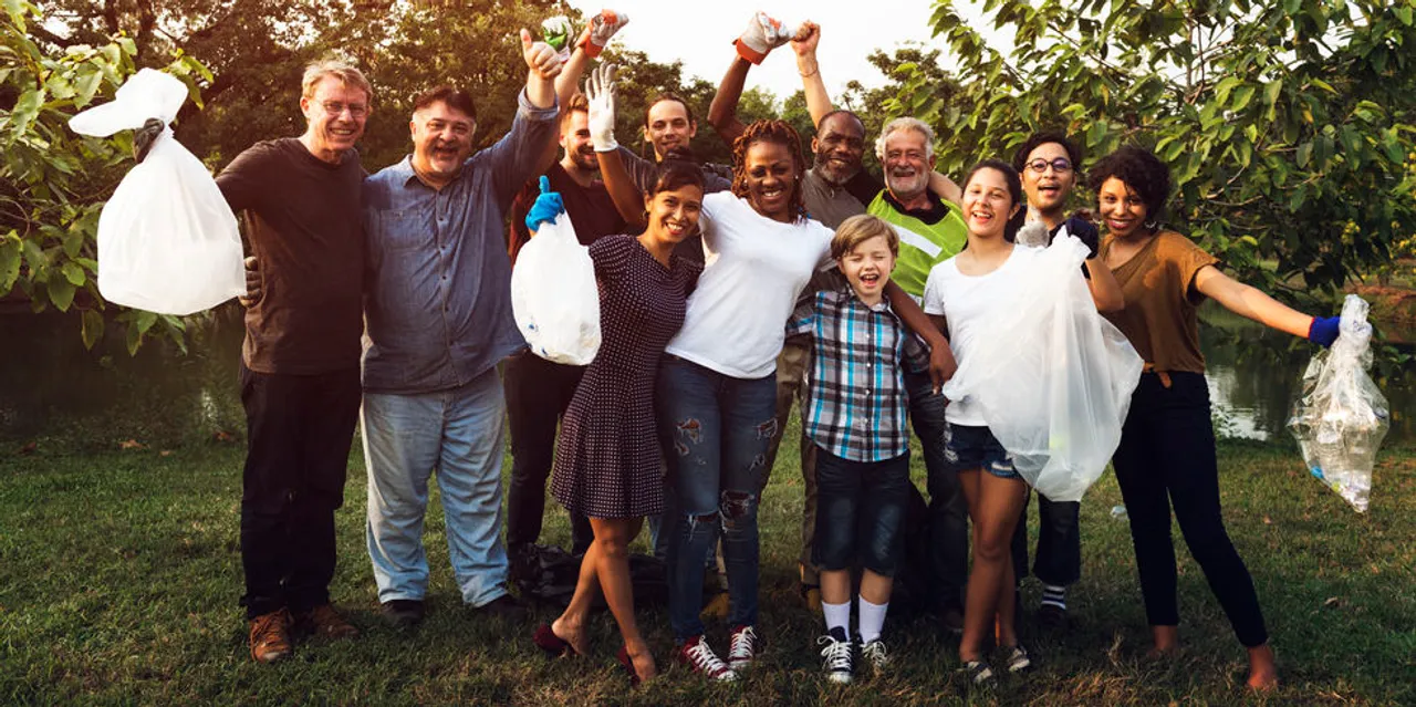 A diverse group of volunteers works at cleaning up a park.