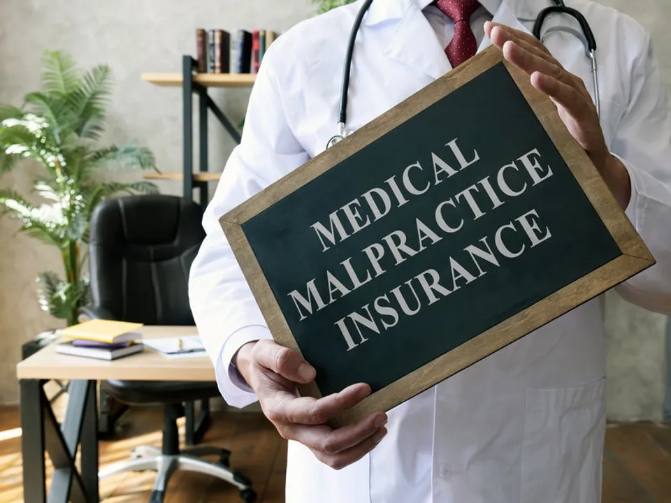 A physician holding a sign saying "medical malpractice insurance"