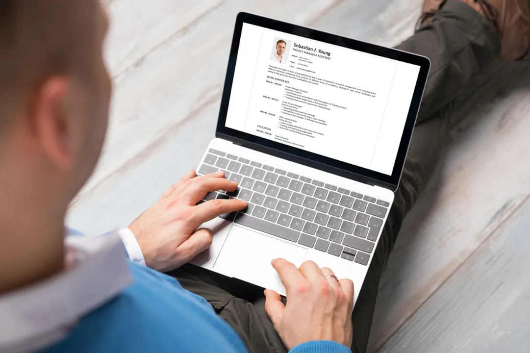 Image shows a doctor working on his CV on a laptop computer