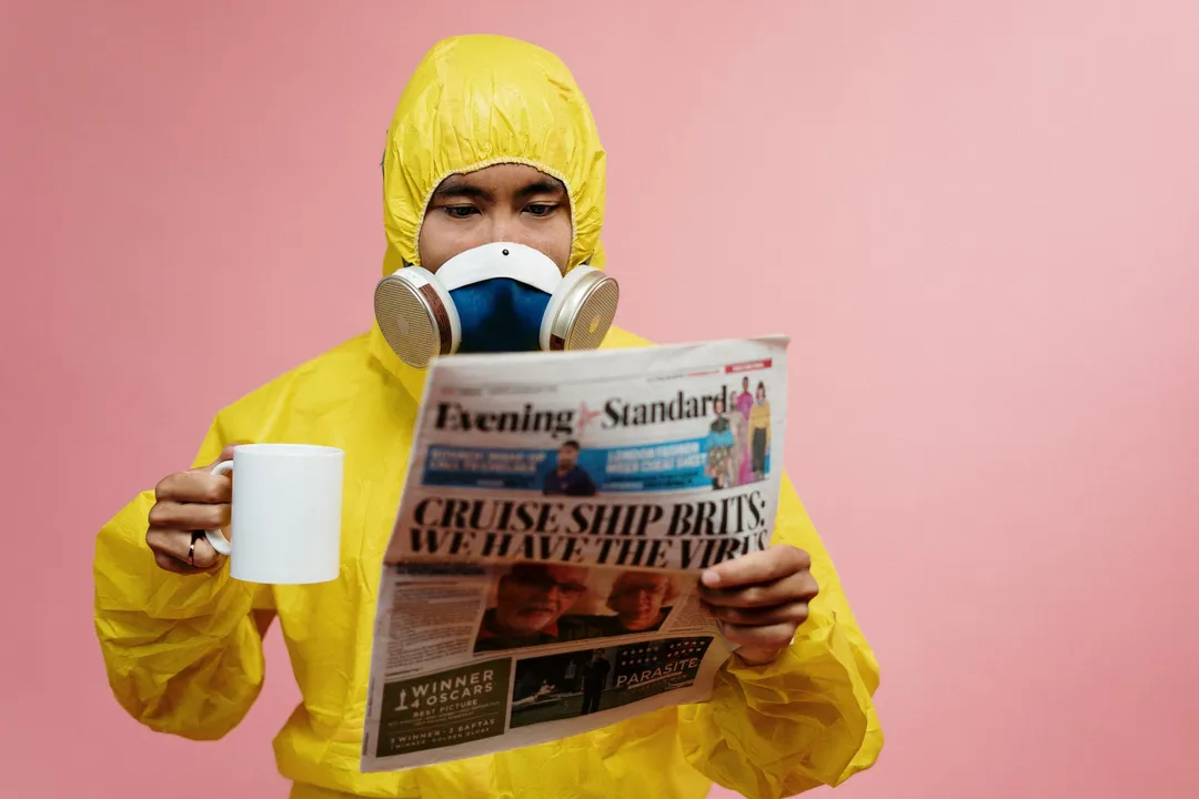 A man in a hazmat suit reads the paper