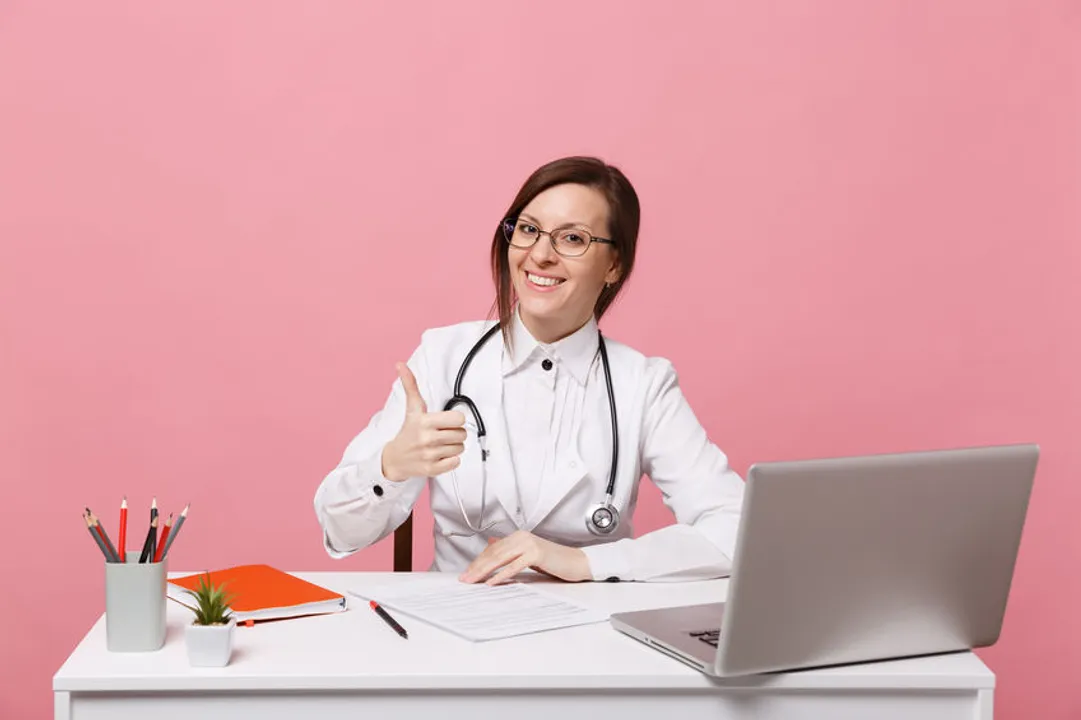 Woman doctor giving thumbs up while using computer