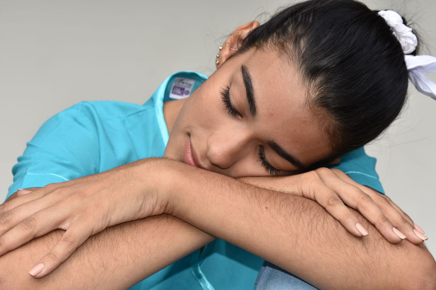 A sleepy female nurse or physician is resting her head on her arms